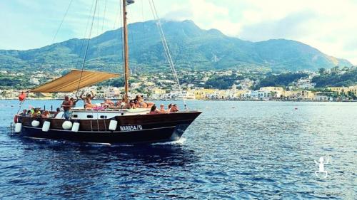 Boat with panoramic views among the crystal clear waters of Ischia in Campania during a family experience with lunch on board